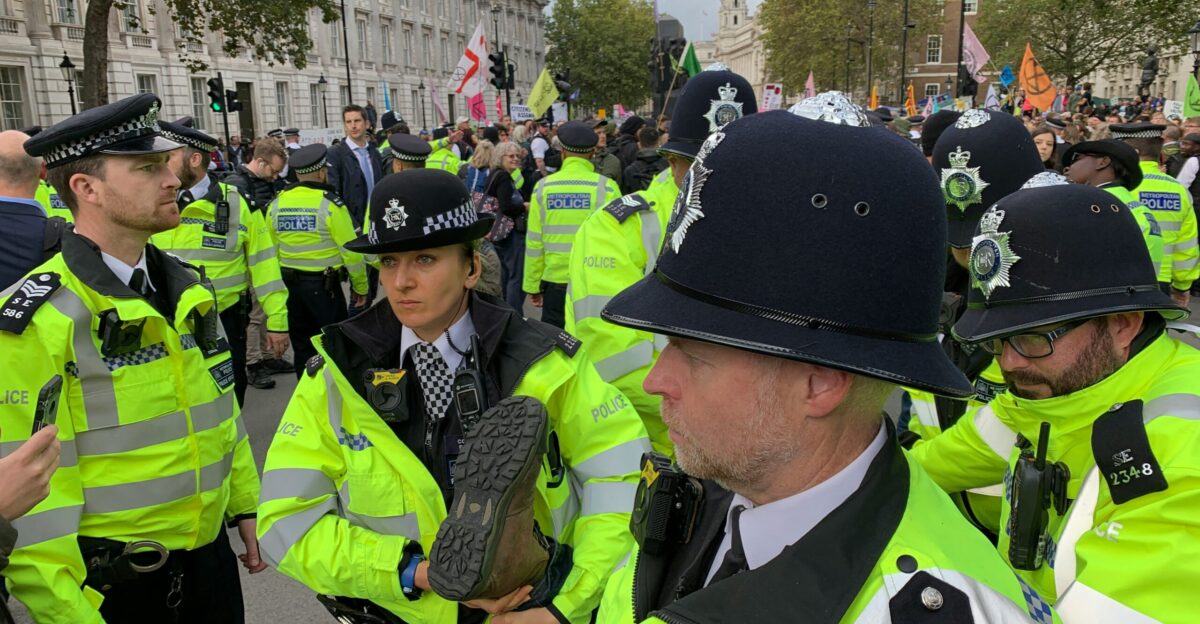 crowd of police officers near people on street beside buildings during daytime
