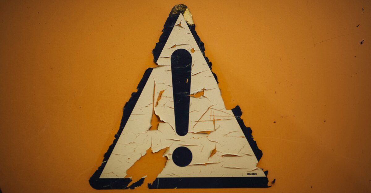 a triangle shaped sign on a yellow wall