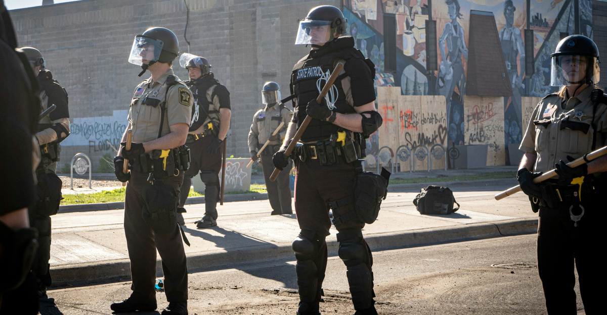 2 men in green and brown uniform standing on gray pavement during daytime