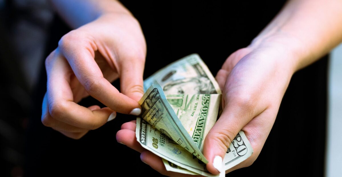 person holding fan of 100 us dollar bill