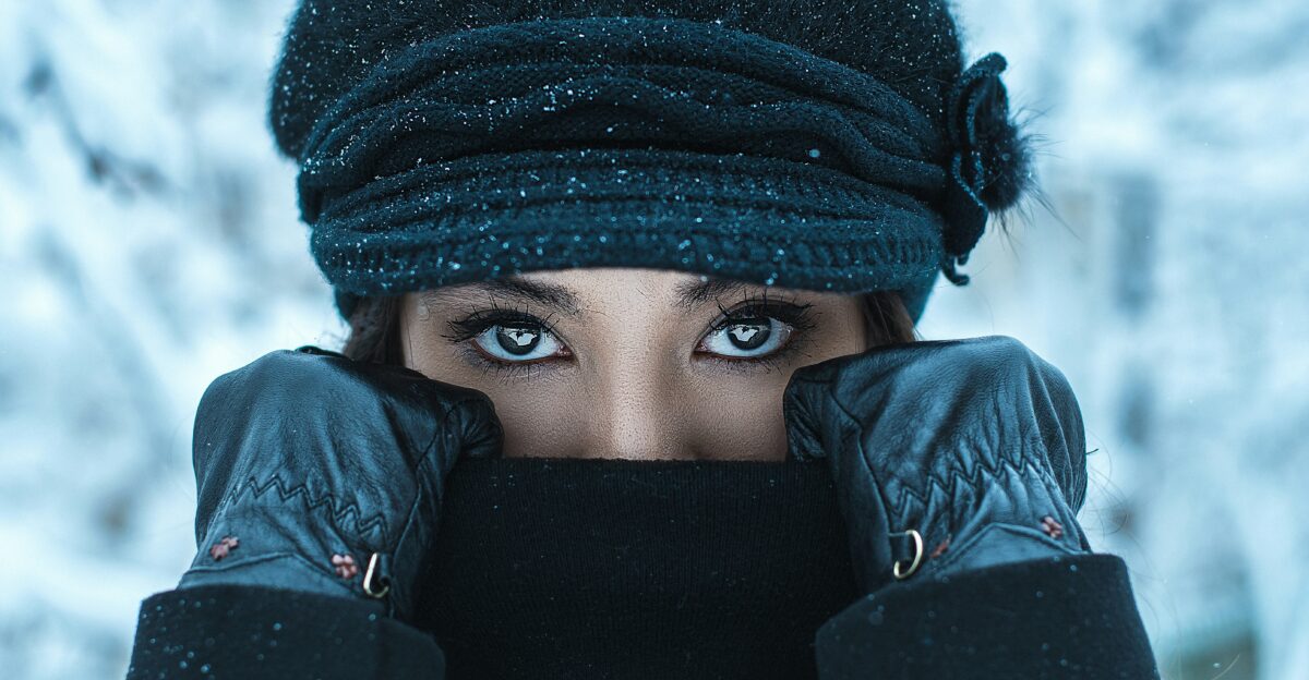 woman in black knit cap covering her face with her hand