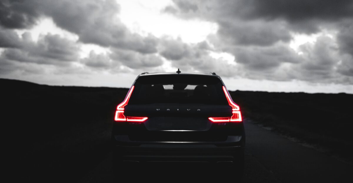 red car on black asphalt road under gray cloudy sky