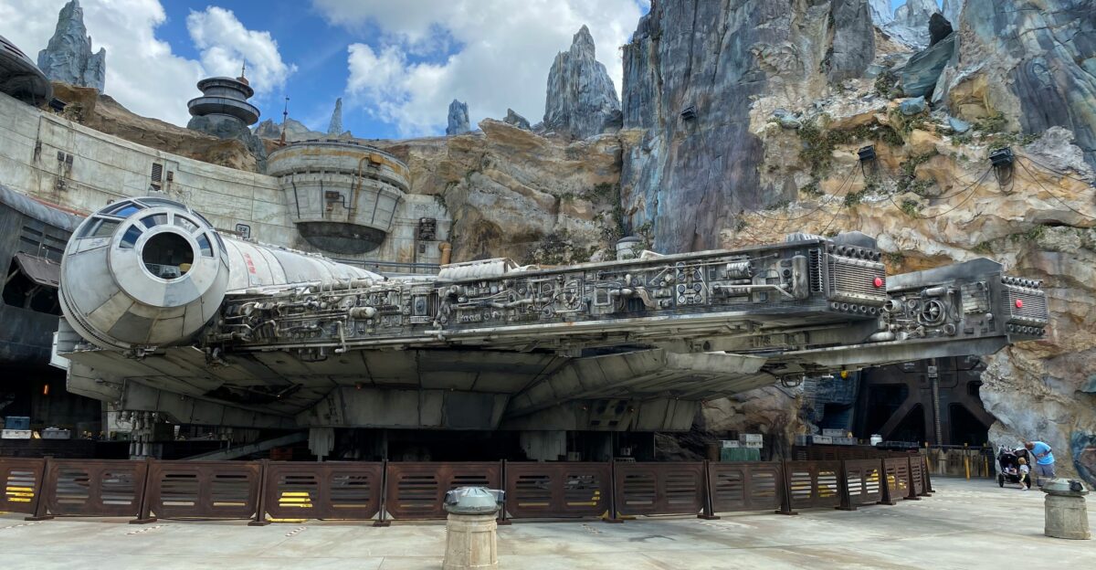 brown wooden bench near gray rock formation under white clouds and blue sky during daytime