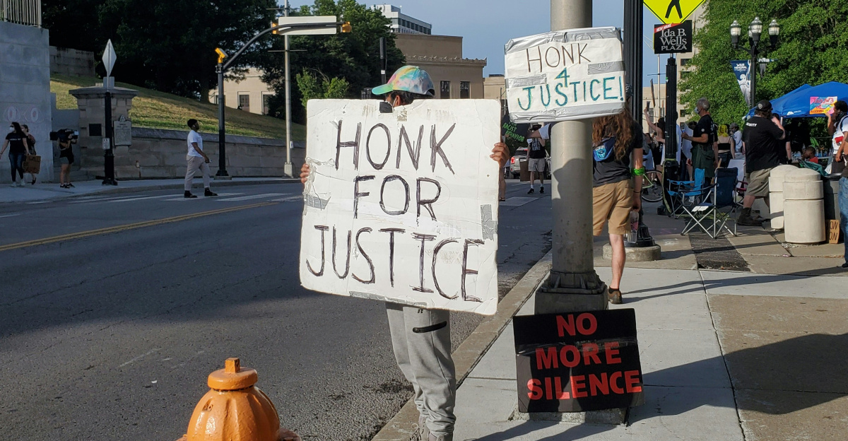 man in gray pants holding white and black signage