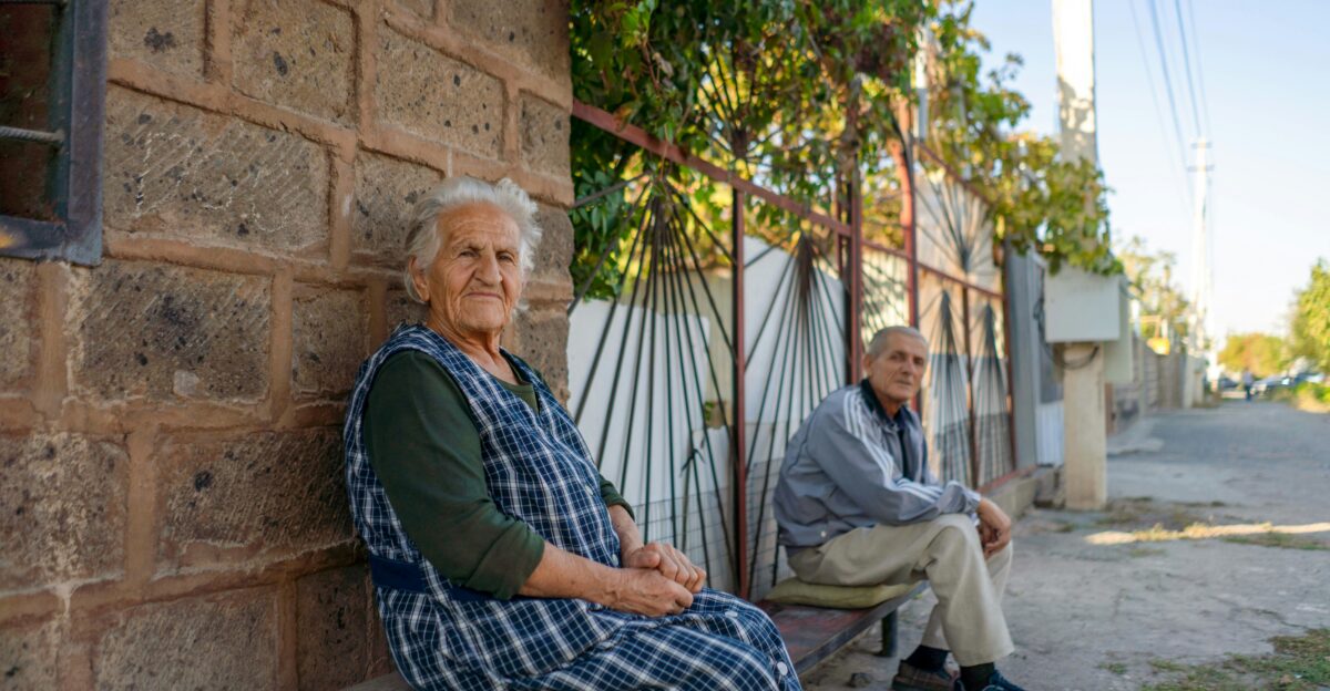 a couple of people sitting on a bench next to a building