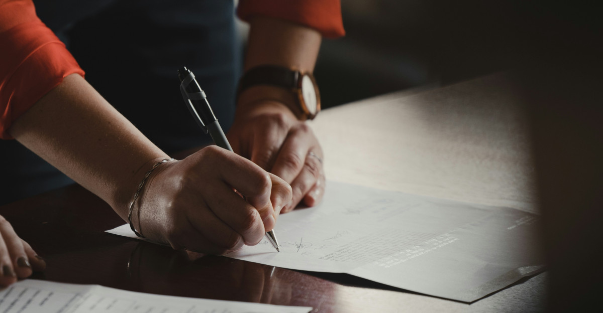 person in orange long sleeve shirt writing on white paper