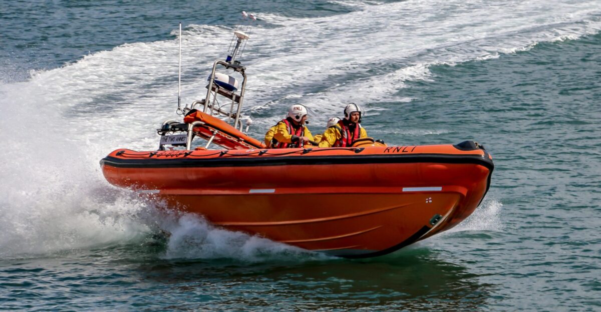 people riding orange and white boat on sea during daytime