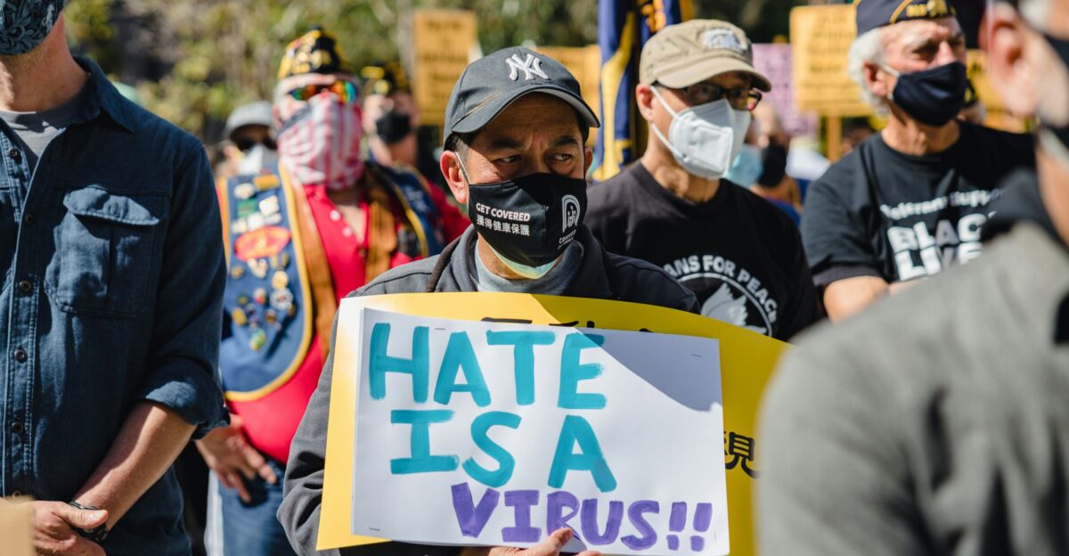 man in black jacket holding white and blue banner