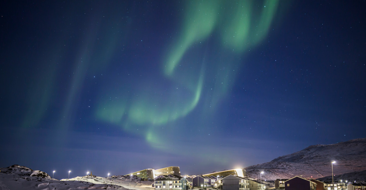 white and brown houses under green sky during night time