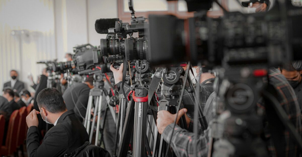 a large group of people in a room with cameras