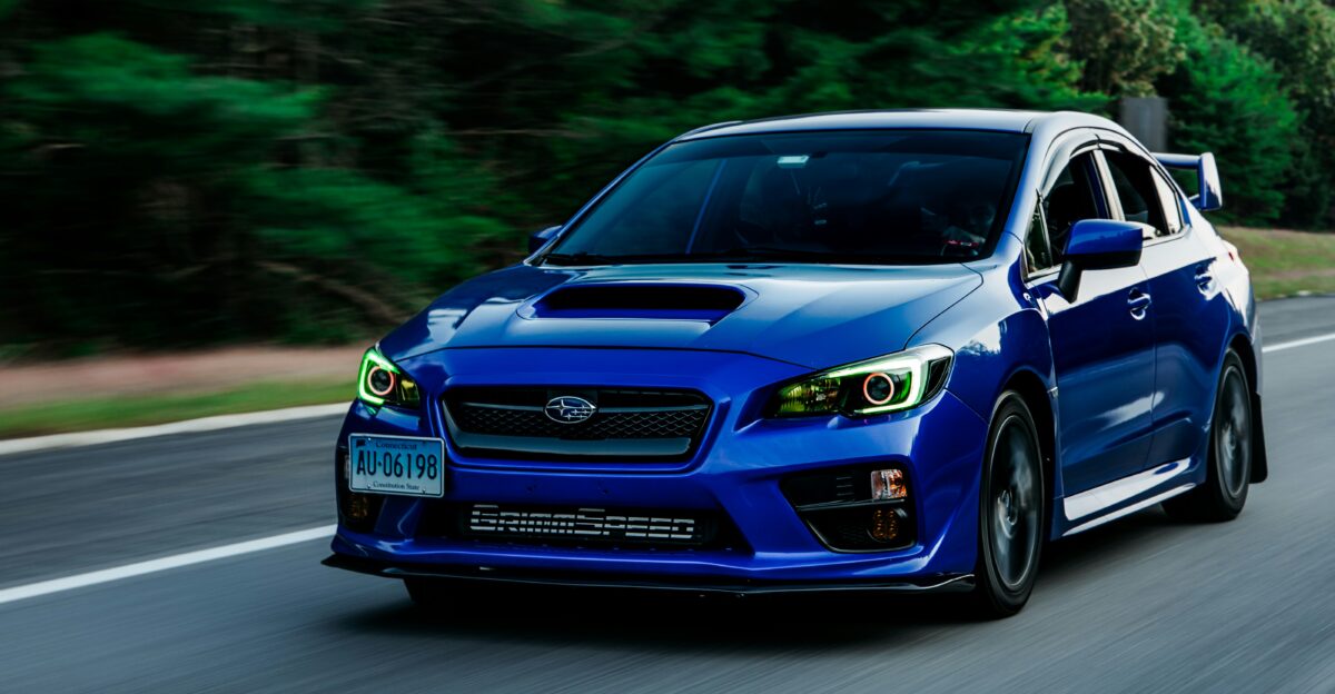 a blue subarunt is driving down the road