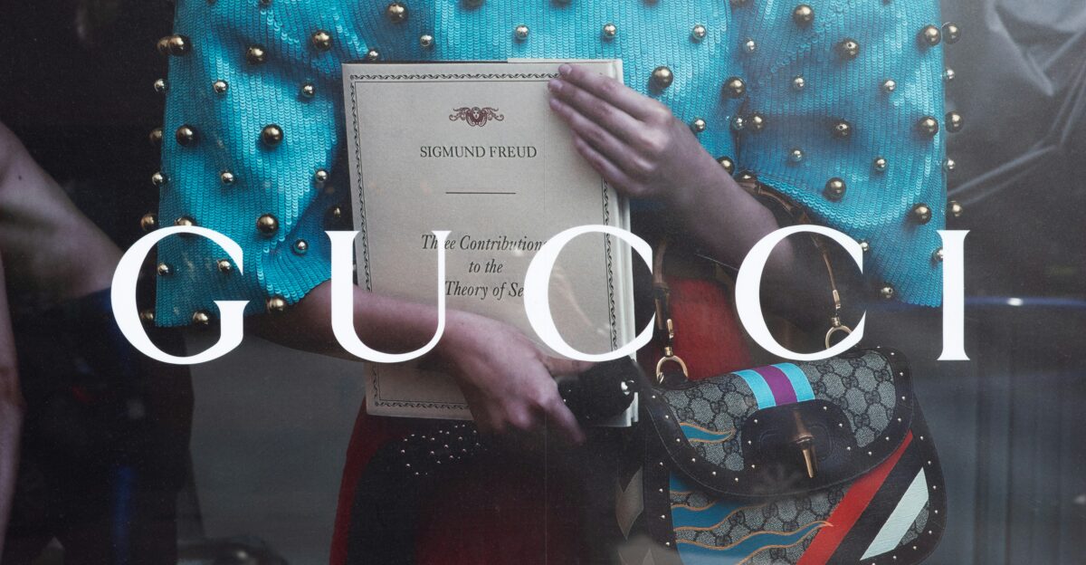 a woman holding a gucci bag in front of a window