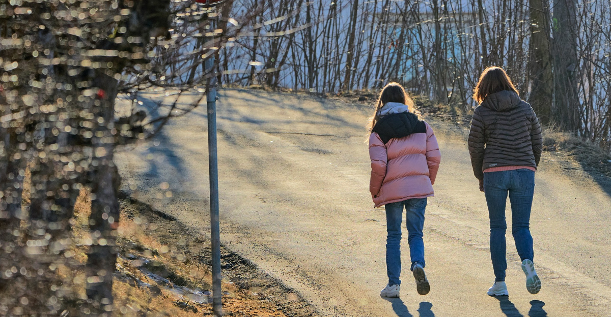 a couple of women walking down a dirt road