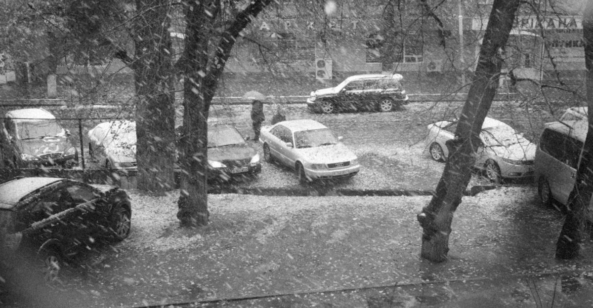 a black and white photo of a parking lot in the snow