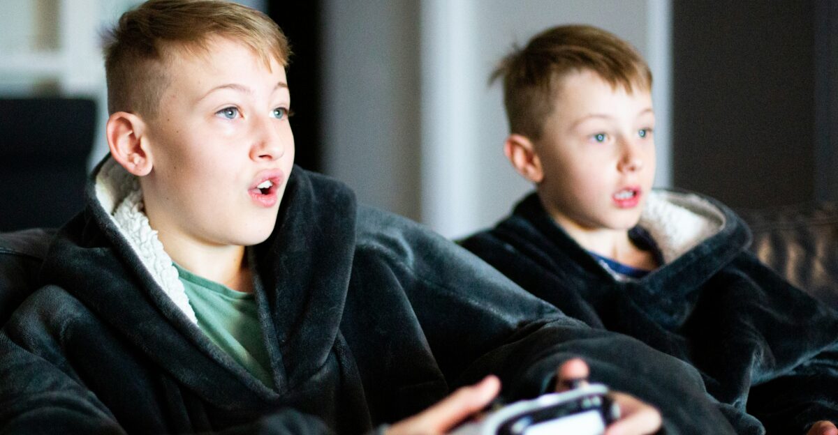 two young boys sitting on a couch playing a video game