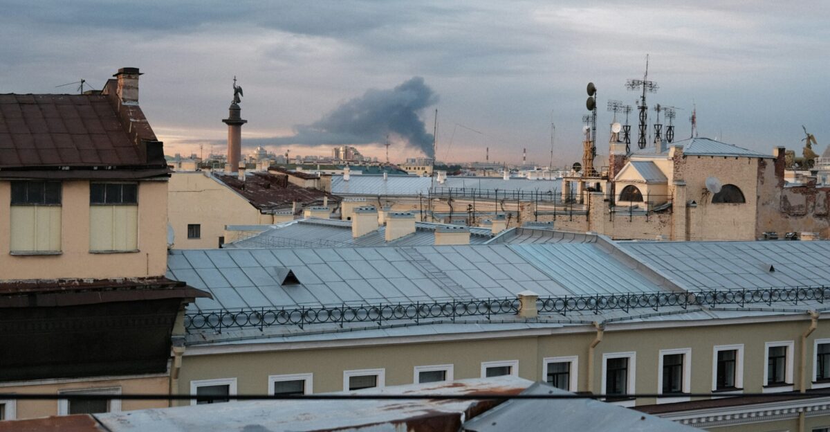 a group of buildings with a smokestack in the background