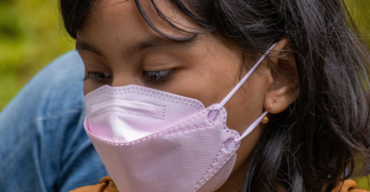 a woman wearing a face mask while looking at her cell phone