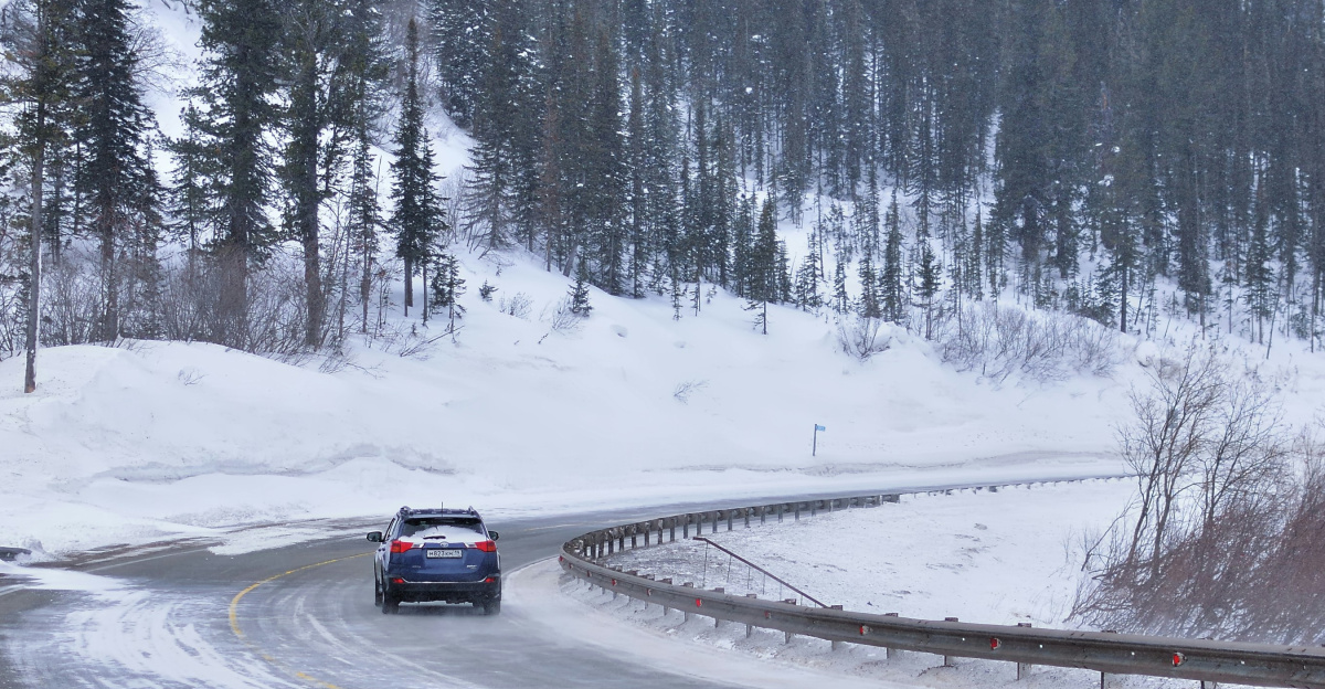 a car driving down a snowy road in the mountains