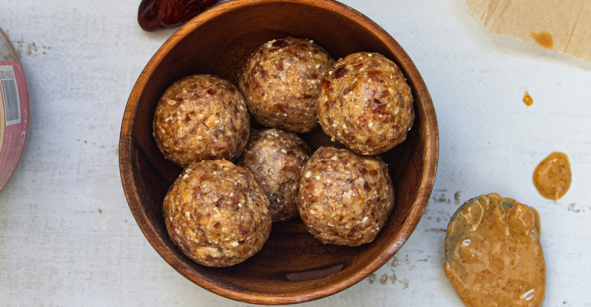 a wooden bowl filled with nuts next to a jar of nuts