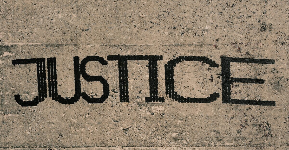 The word justice written in black ink on a concrete surface photo