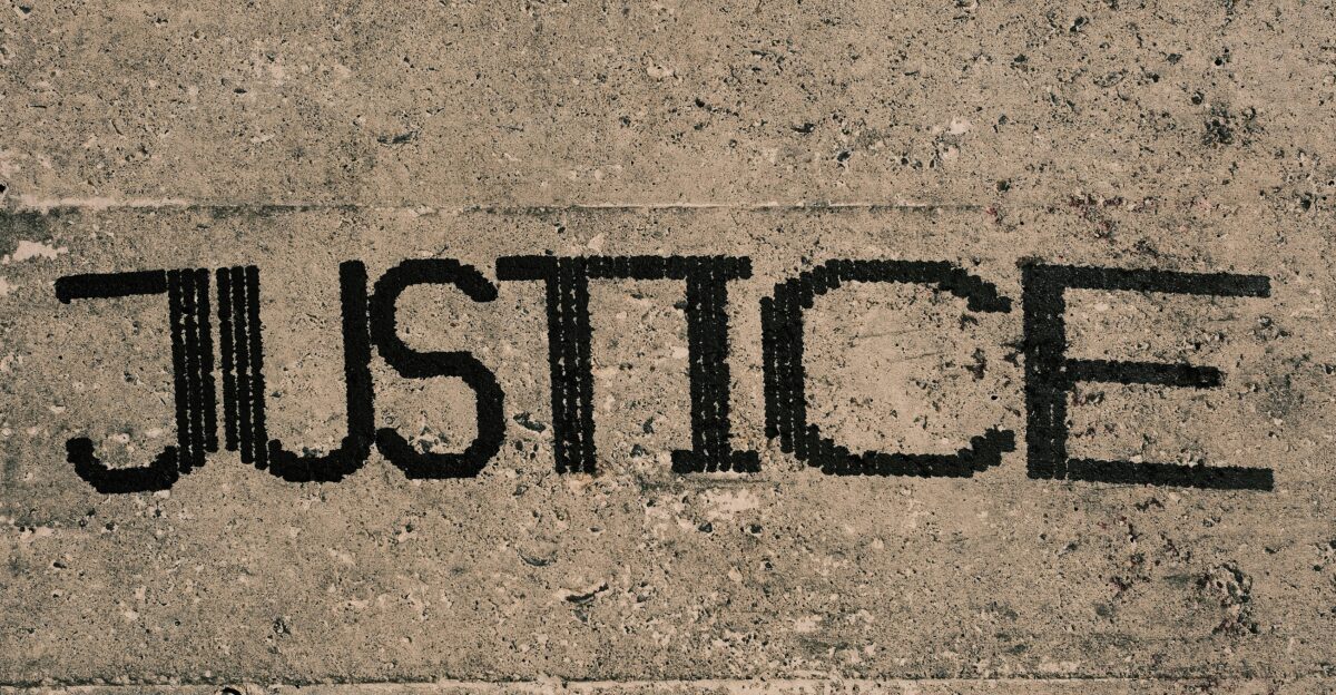the word justice written in black ink on a concrete surface