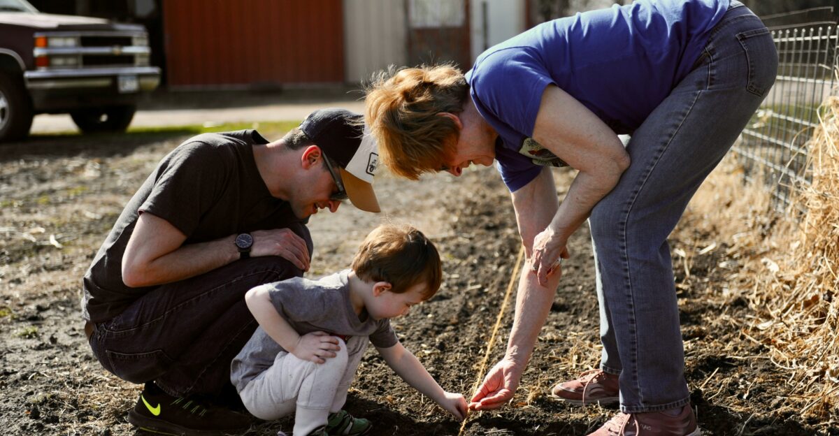 a woman and two children are looking at a plant