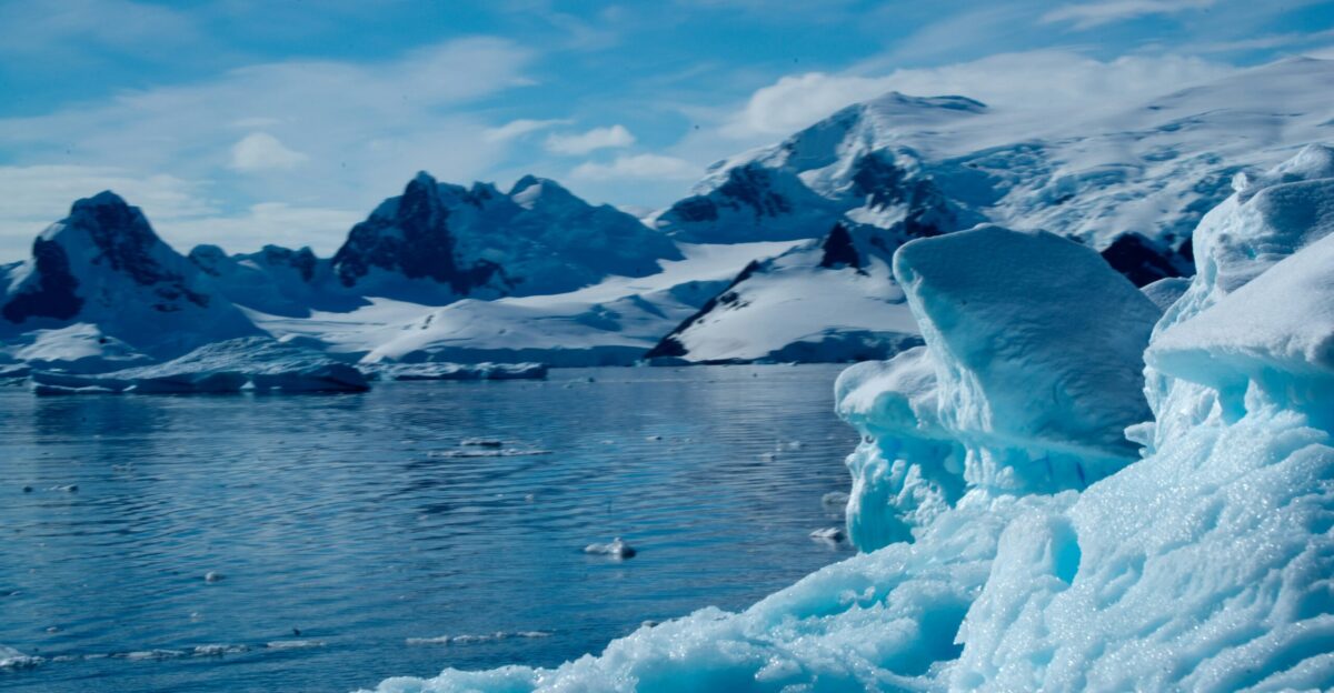 a large iceberg floating on top of a lake surrounded by snow covered mountains