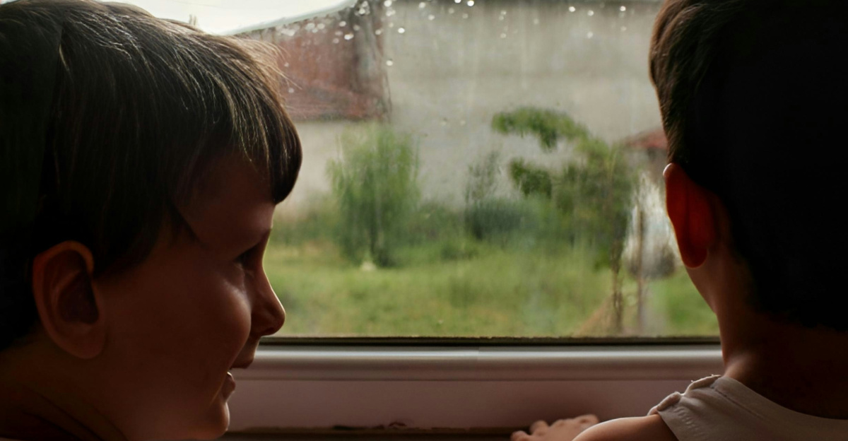 two young boys looking out of a window