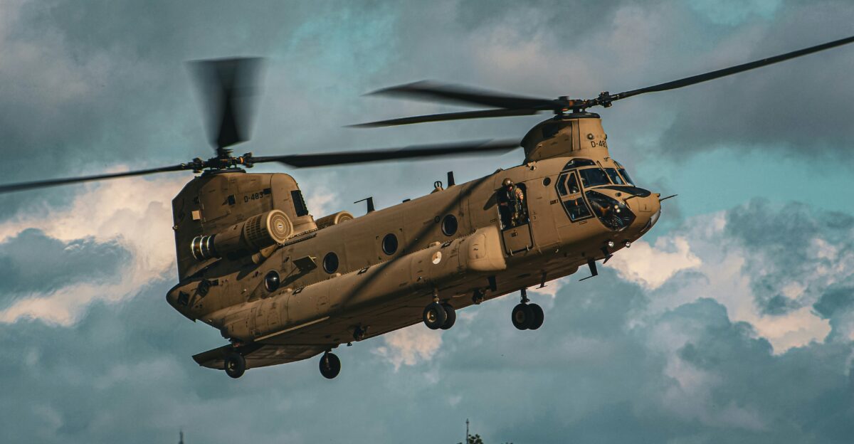 a large military helicopter flying through a cloudy sky