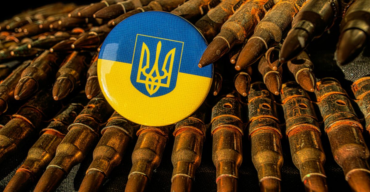 a blue and yellow button sitting on top of a pile of bullet shells