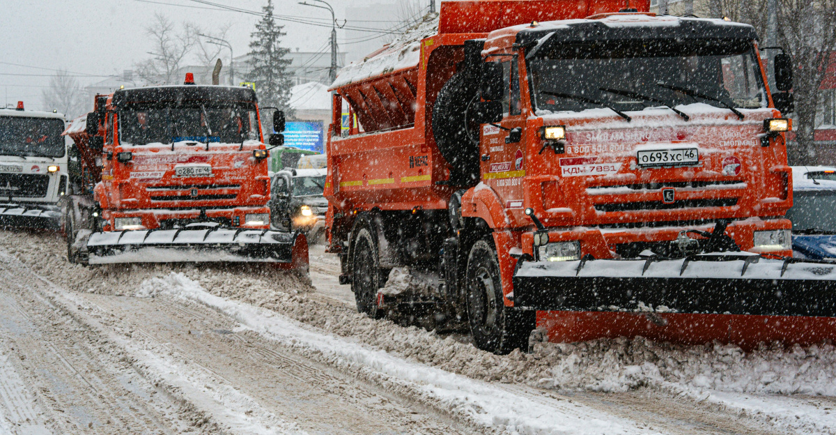 a couple of trucks driving down a snow covered road