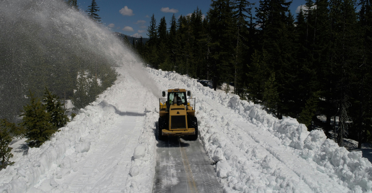 a snow plow driving down a snow covered road