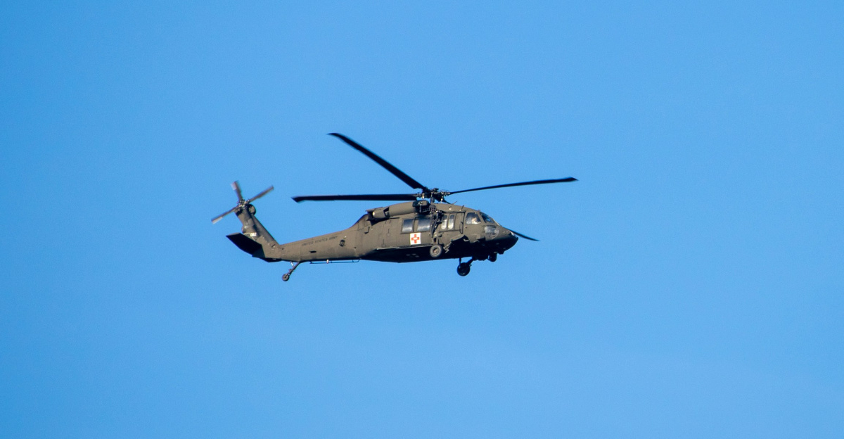 a military helicopter flying through a blue sky