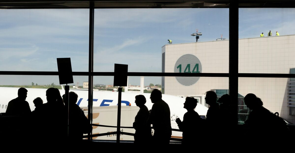 a group of people standing in front of an airport window