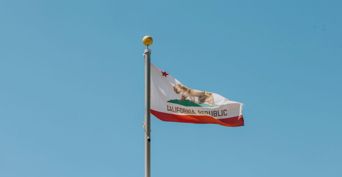 A flag flying in the wind on top of a building