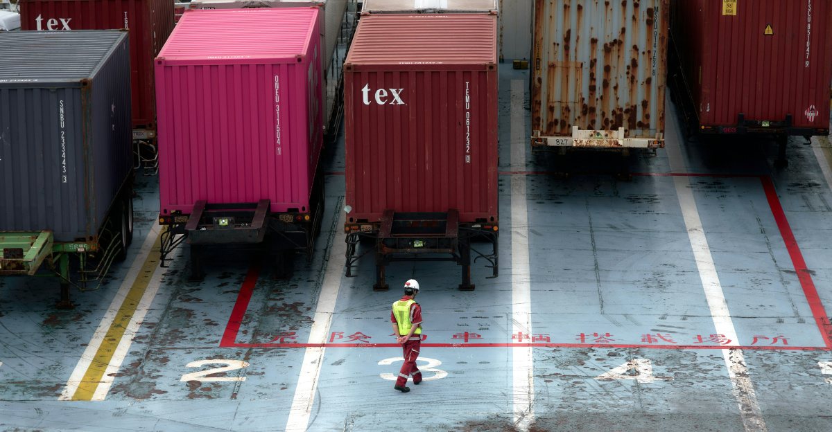 A man standing in a parking lot next to lots of shipping containers