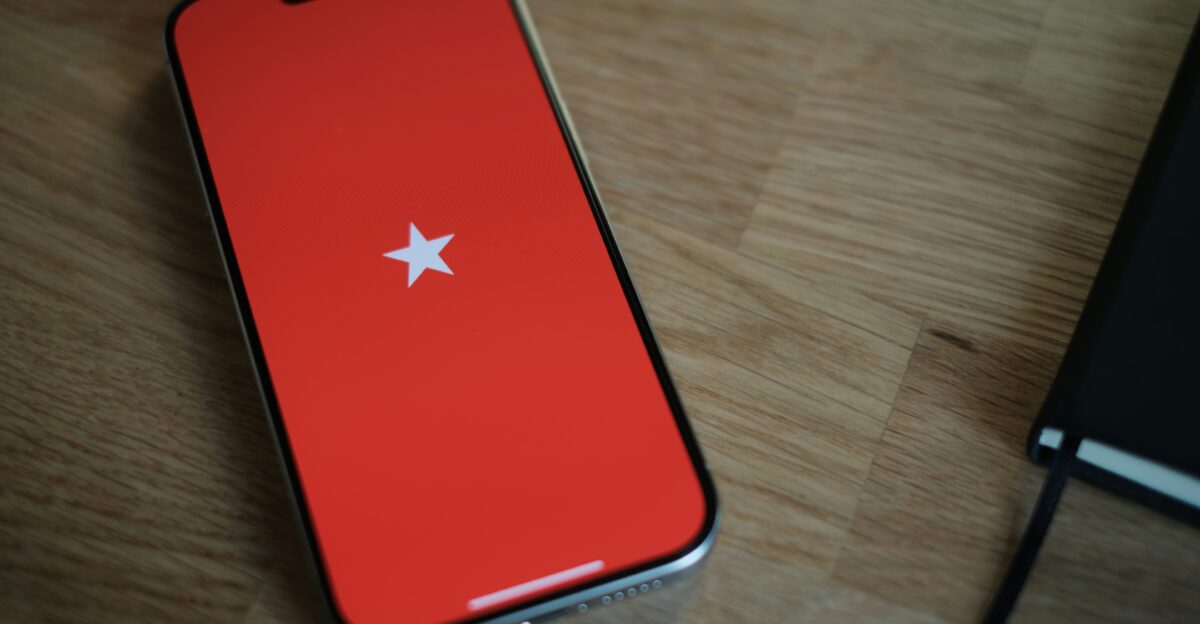 A red cell phone sitting on top of a wooden table