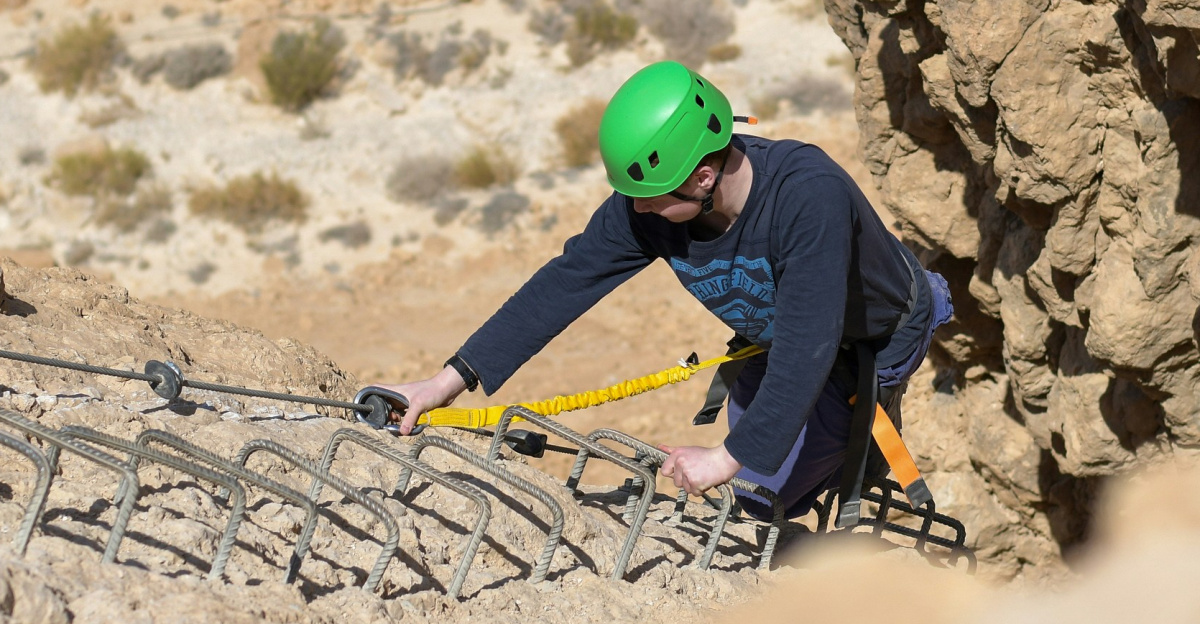A man in a green helmet climbing up a mountain