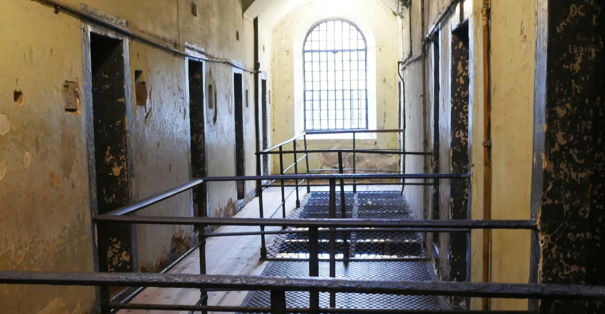 A long hallway with metal railings leading to a window