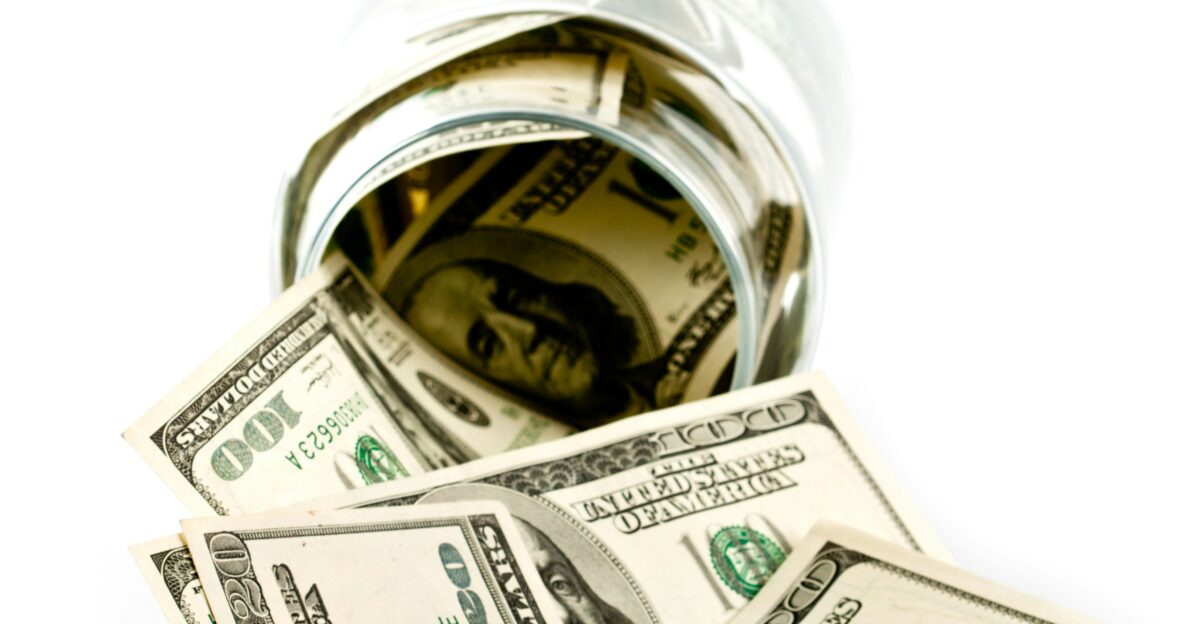 A glass jar filled with money sitting on top of a table