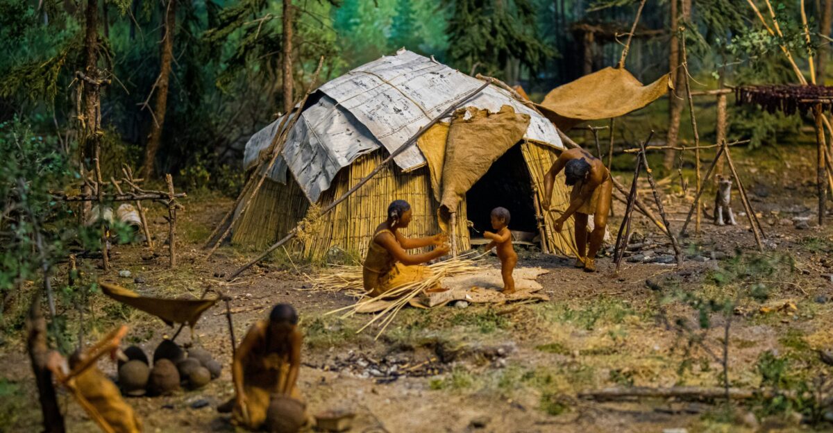 People are shown living in a primitive settlement