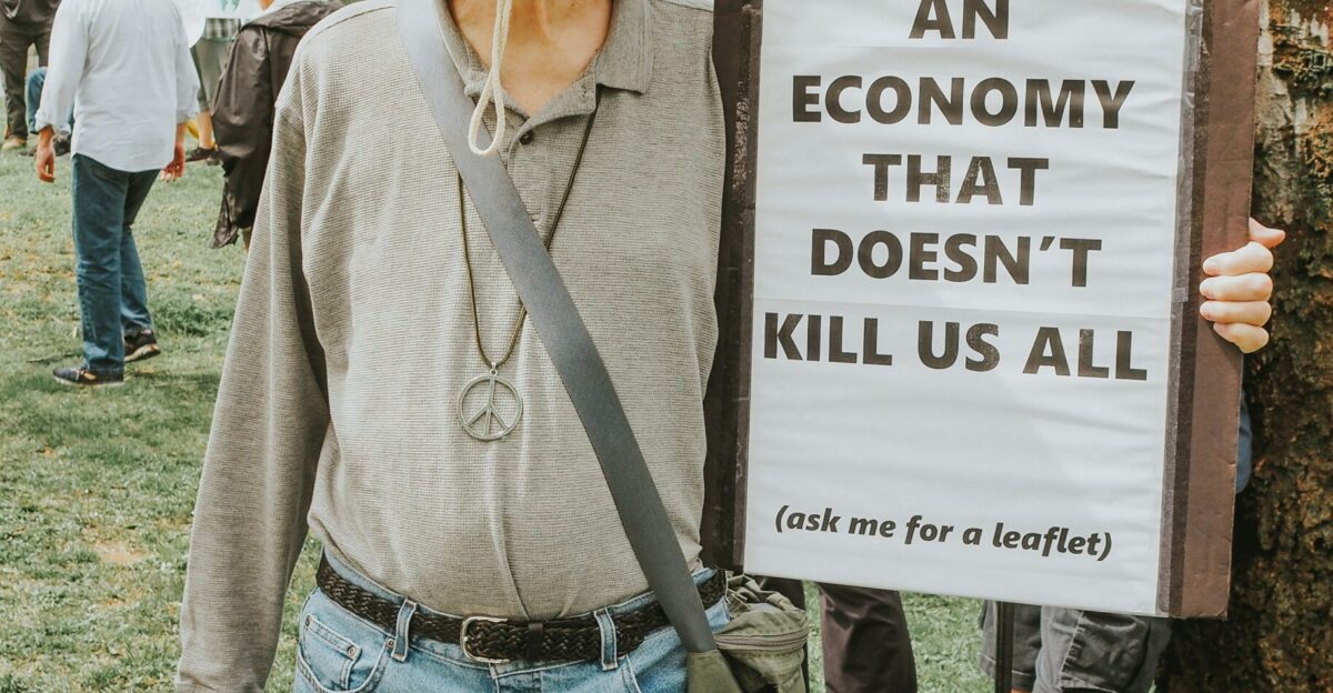 Protester holds sign calling for an end to harmful economy