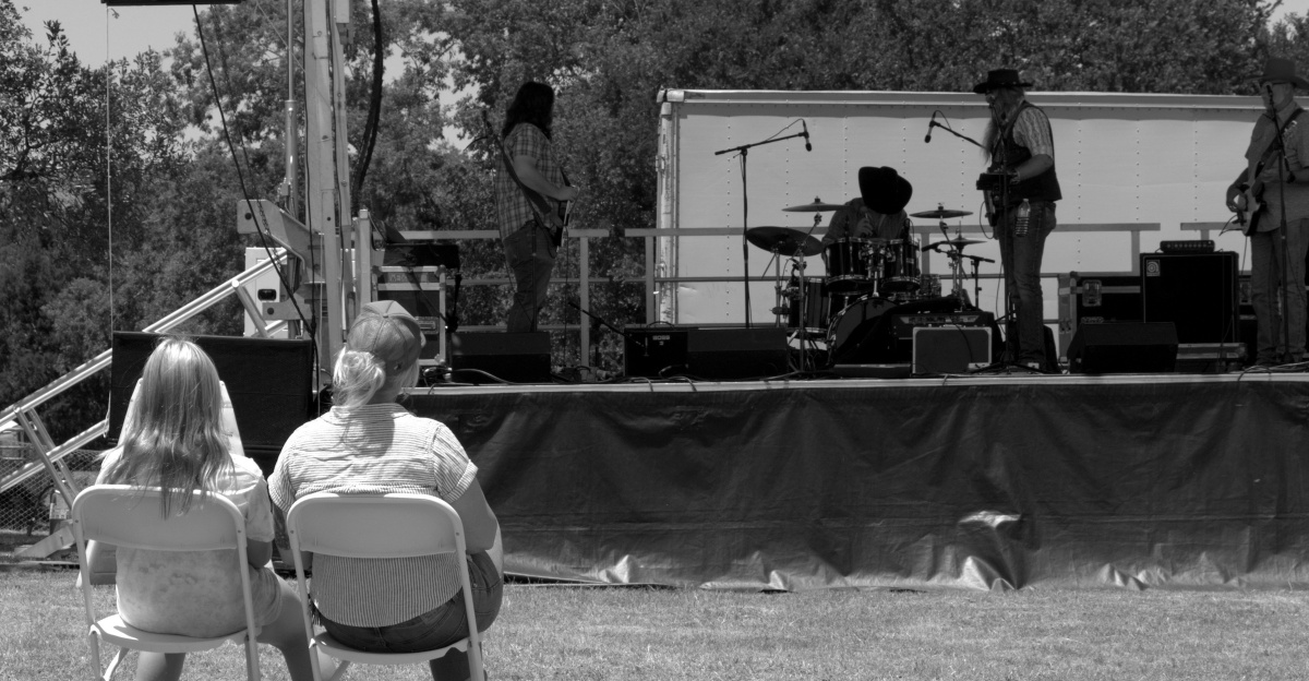 People watch a band performing on an outdoor stage.