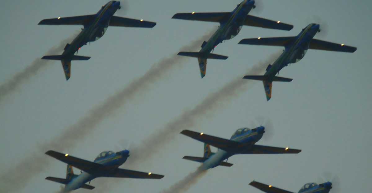 Six airplanes fly in formation, leaving smoke trails.