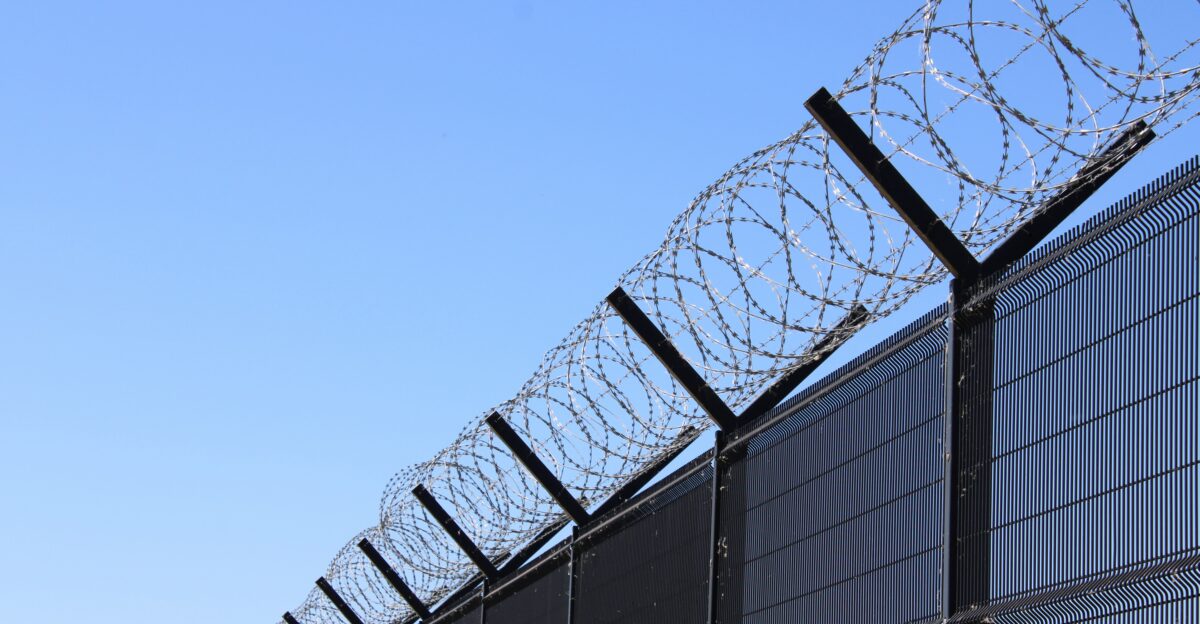 Razor wire sits atop a tall protective fence