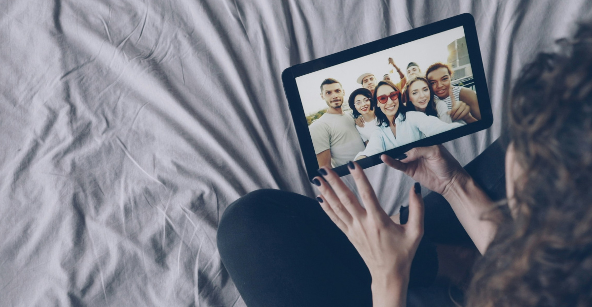 Woman video calling friends on tablet in bed