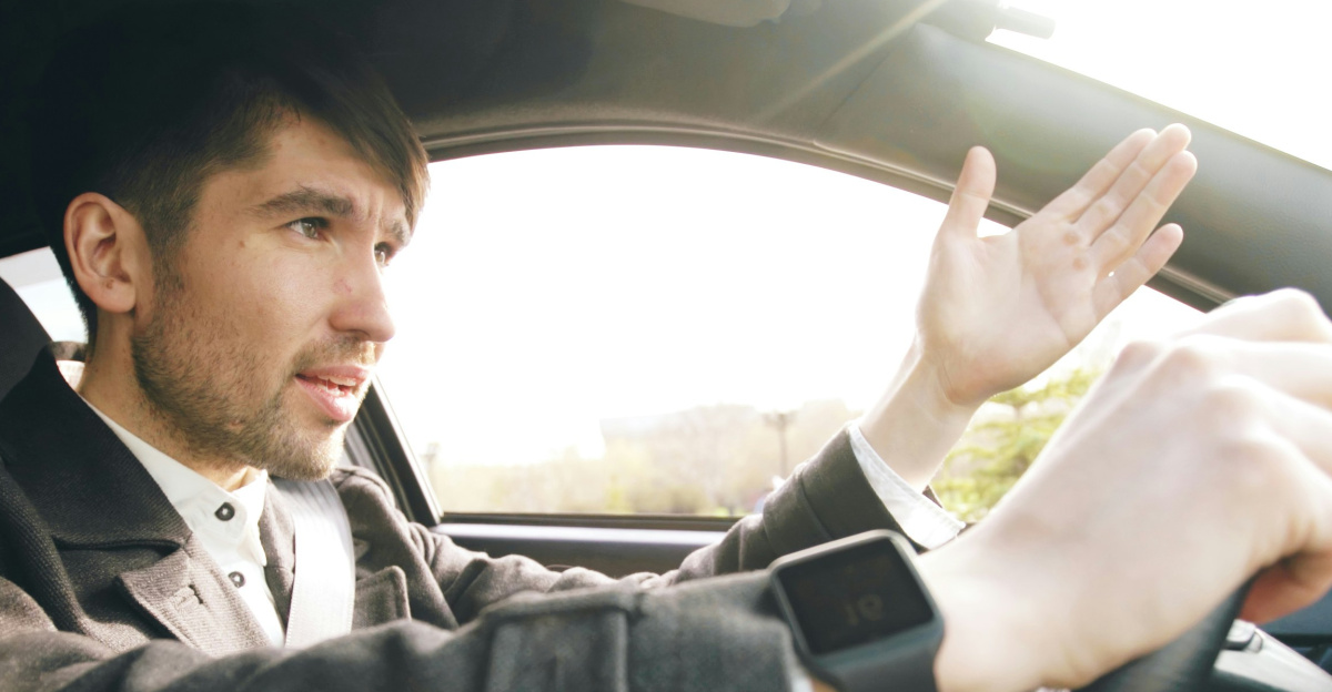 Man driving a car, gesturing with hand.