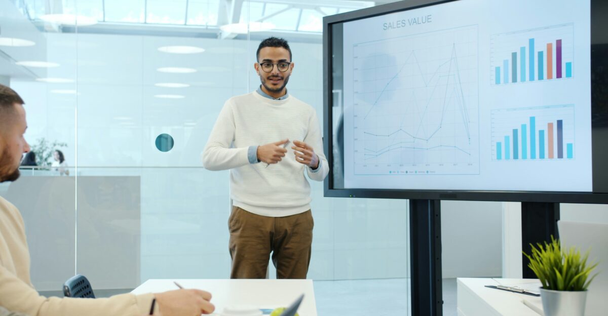 Man presents charts on a screen during a meeting