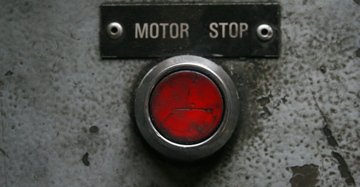 Red motor stop button on a metal panel