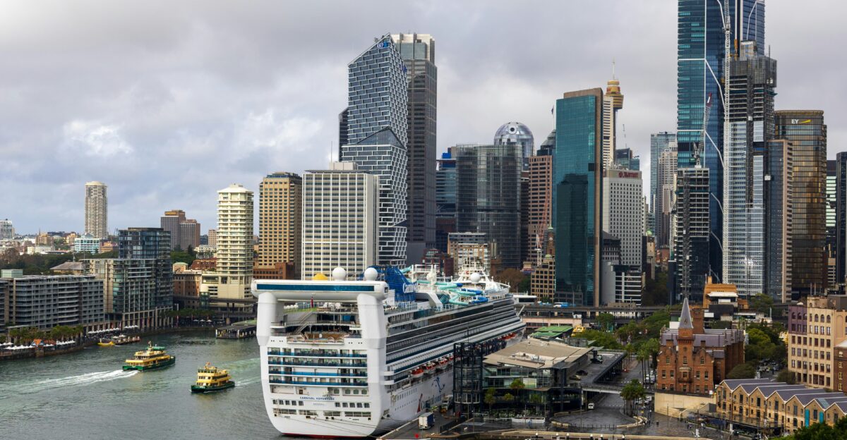 Cruise ship docked in a harbor with city skyline